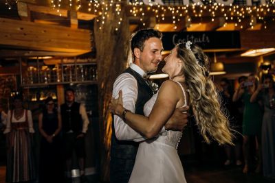 Braut und Bräutigam tanzen beim Hochzeitsfest unter Lichterketten – stimmungsvolle Aufnahme.