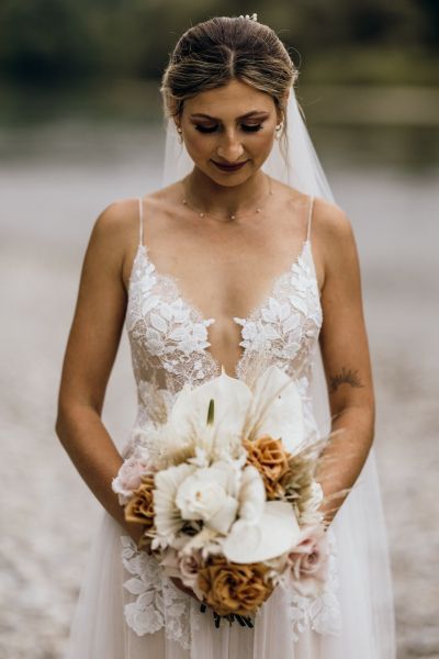 Porträt der Braut mit Brautstrauß, feines Spitzenkleid und sanfte Farben.