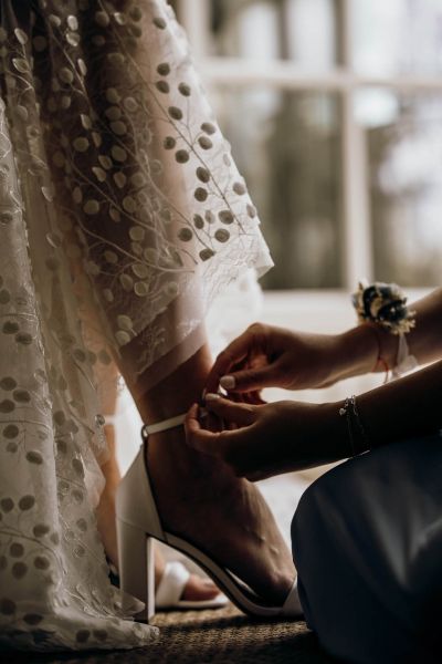 Nahaufnahme der Braut, wie sie ihre Hochzeitsschuhe anzieht – elegantes Detailfoto.