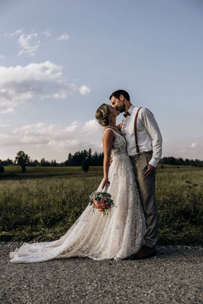 Brautpaar küsst sich im Sonnenuntergang – romantische Sommerhochzeit.
