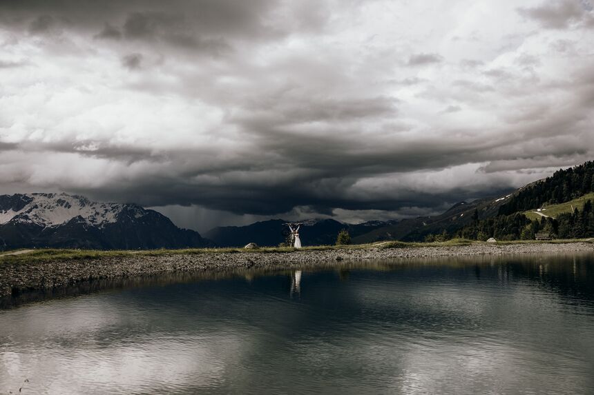 Brautpaar in den Alpen vor dramatischer Wolkenkulisse – imposantes Hochzeitsfoto mit Bergblick.