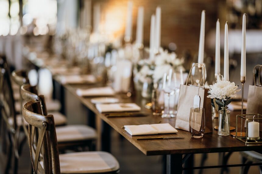 Festlich gedeckter Hochzeitstisch mit weißen Kerzen, Glasvasen und Blumenschmuck in sanften Farben.