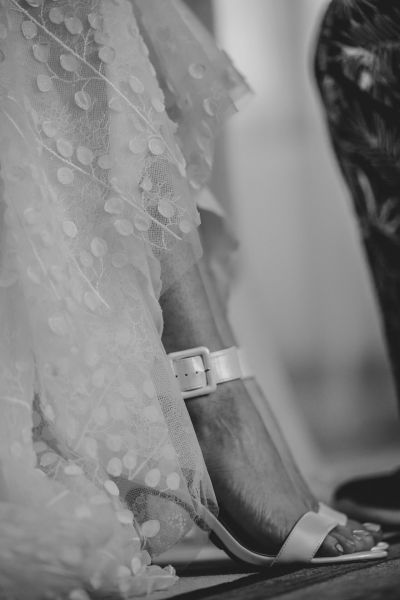 Detailaufnahme von Brautschuhen und Spitzenstoff – künstlerisches Schwarz-Weiß-Foto.