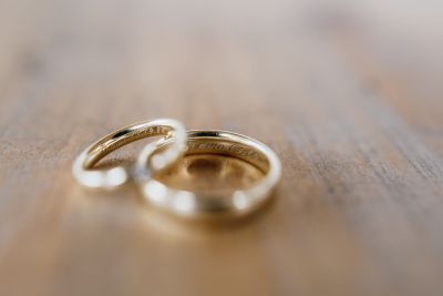 Goldene Eheringe mit Gravur auf Holztisch – symbolisches Detailfoto einer Hochzeit.